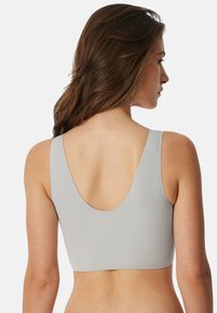 Grijze sportbeha met een gladde textuur, brede schouderbanden en een diepe ronde rugontwerp. Heeft een aangesloten pasvorm voor comfortabel draagcomfort.