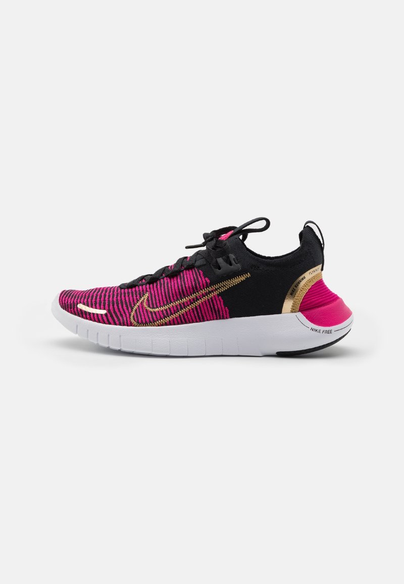 Chaussure de course Nike basse noire et rose avec swoosh doré, semelle blanche flexible et lacets noirs, vue de côté.
