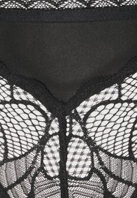 Zwarte kanten lingerie met een bloemmotief, voorzien van een gladde zwarte tailleband. De textuur is doorschijnend en delicaat, wat het ontwerp accentueert.