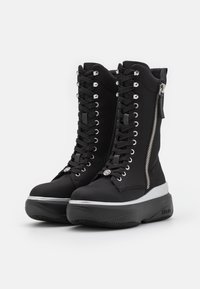 Botas de plataforma negras con una silueta elegante, que presentan una combinación de cierre de cordones y cremallera, acentos metálicos y una suela de goma texturizada.