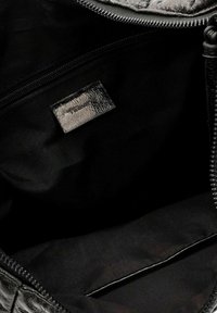 Interno di una borsa a tracolla in pelle nera con texture liscia, chiusura con cerniera, etichetta e fodera in tessuto nero. Non presenta scomparti aggiuntivi.