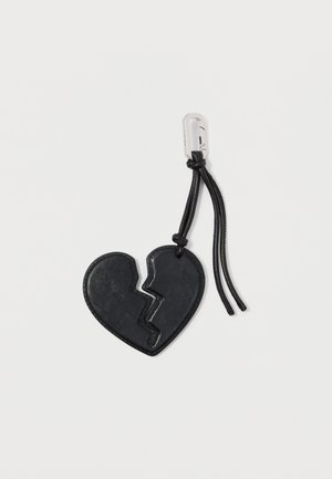 Porte-clés en cuir noir en forme de cœur avec un design de cœur brisé, attaché à un cordon noir avec un clip en argent. Texture lisse.