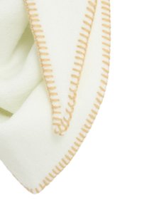 Manta de lana verde claro con una textura suave, que presenta un hilo en color durazno contrastante a lo largo de los bordes y un pliegue triangular.