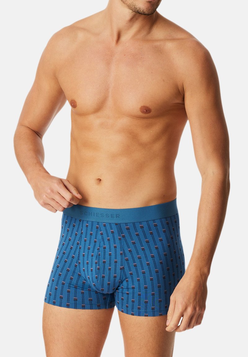 Blaue Boxershorts mit einem Muster aus vertikalen Linien und roten Akzenten, aus weichem Stoff gefertigt, mit einem elastischen Bund und Markenlogo.