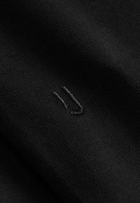 Material textil negru cu o textură canelată, având un mic logo brodat subtil într-un fir de culoare neagră asortat.