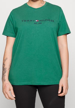 Vihreä puuvillapaita lyhyillä hihoilla, pyöreällä kaula-aukolla ja navy- ja punaisella brodeeratulla "TOMMY HILFIGER EST. 1985" -logolla rinnassa.