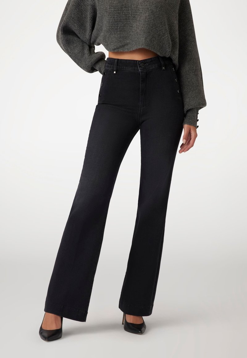 Black, high-waisted jeans with a flared leg, featuring side button accents and a smooth denim texture, paired with a cropped gray sweater.