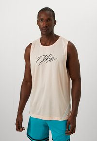 Helles rosa Netz-Top mit einem schwarzen "Nike"-Logo, rundem Ausschnitt und kontrastierendem Besatz, kombiniert mit blauen Shorts mit schwarzen Streifen.