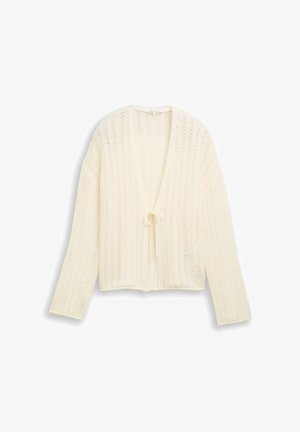 Roomkleurig vest met open gebreide structuur, lange mouwen en een kleine sluiting met een strik aan de voorkant, plat gelegd op een witte achtergrond.