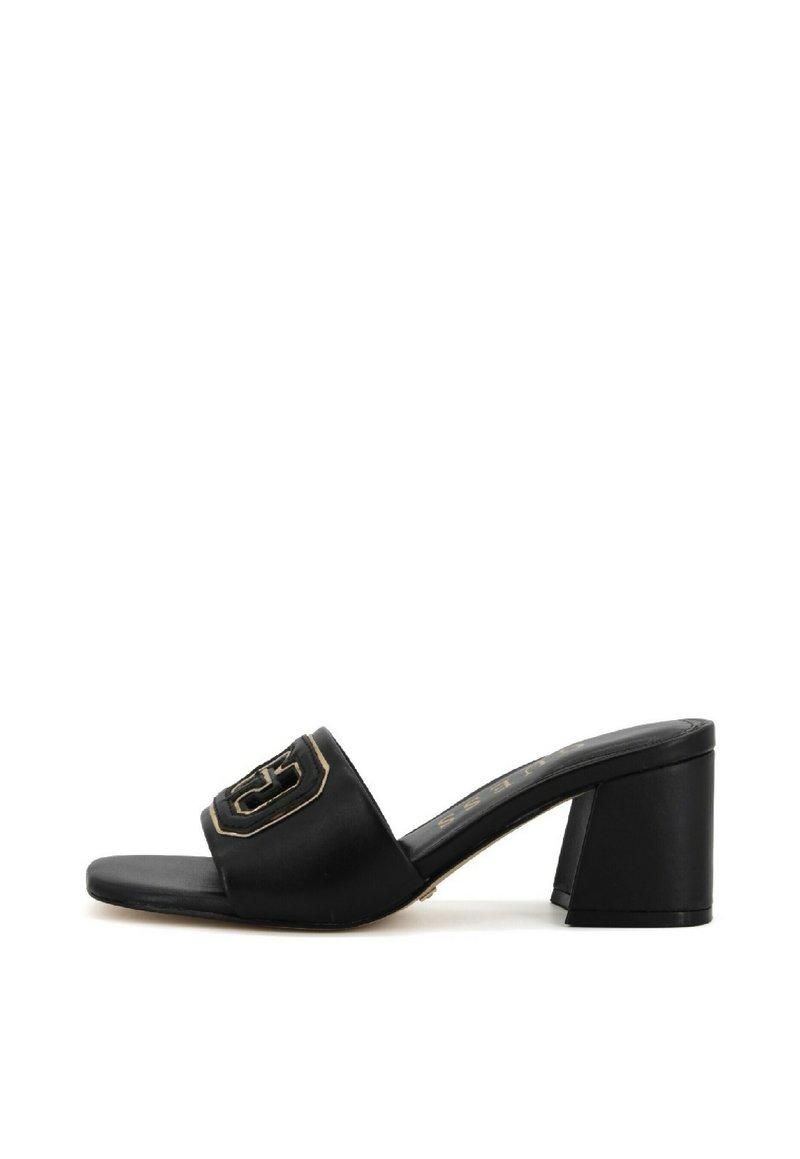 Black heeled slide sandal made of smooth synthetic material. Features a wide strap with a gold accent logo and chunky block heel.