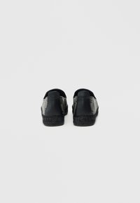 Μαύρα και γκρι παπούτσια στιλ εσπαντρίγιες με πλεκτή σόλα από τζούτα και λείες δερμάτινες λεπτομέρειες. Στρογγυλεμένος πίσω σχεδιασμός, χαμηλό τακούνι και ελάχιστες λεπτομέρειες.