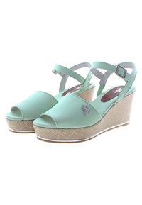 Vihreät wedge-sandaalit avonaisella varpaalla, säädettävällä nilkkahihnalla, kudottu rakenne ja hopeinen yksityiskohta päällä.
