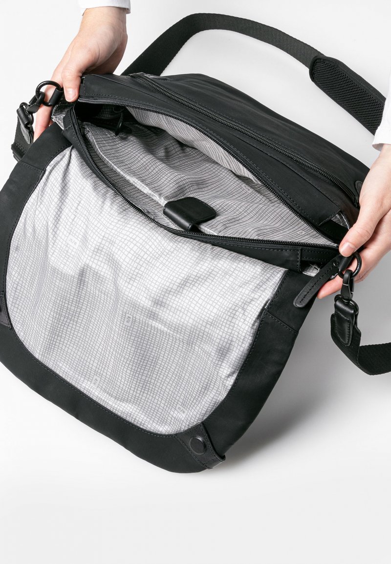 Black leather messenger bag with gray patterned lining, zip closure, and adjustable strap. Features two hand-held clips and interior pocket.
