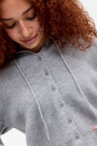 Jasnoszara, ribbed sweter z kapturem, z przodem zapinanym na guziki i fakturowanym materiałem. Guziki w średnim szarym kolorze podkreślają design.