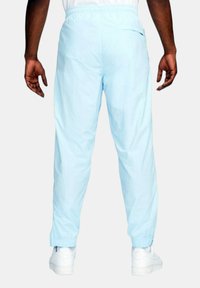 Ljust blå träningsbyxor med elastisk midja, avsmalnande ben och elastiska muddar vid anklarna. Minimalistisk design utan synliga mönster.