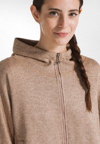 Ljust brunt zip-up hoodie med metallisk lyster, hög krage och kontrasterande sömmar. Slät textur och avslappnad passform.