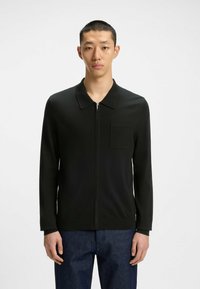 Cardigan nero con zip e colletto, dotato di tasca sul petto e maniche lunghe, realizzato in un tessuto liscio e texture.