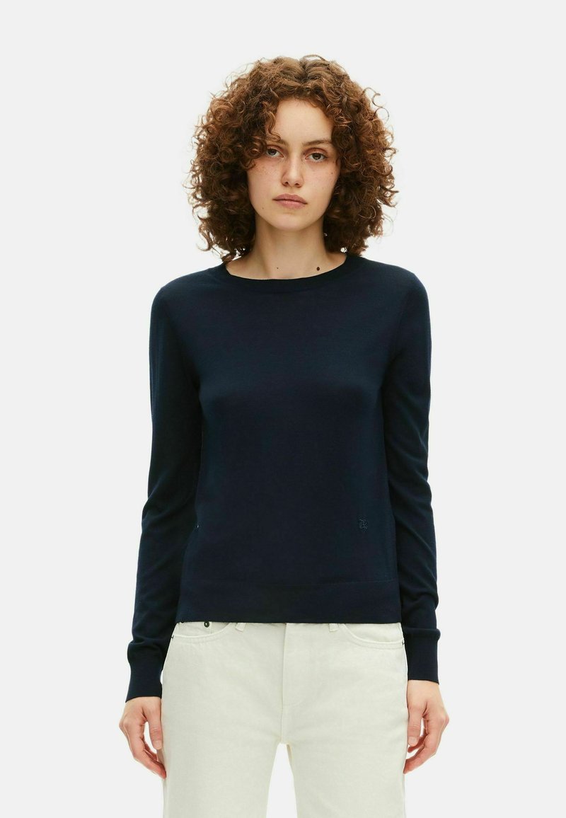 Maglione a maniche lunghe di colore blu navy, con scollo a barchetta e polsini a coste. Il tessuto appare liscio e leggermente aderente.