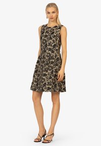 Ärmelloses Kleid mit floralem Muster in Schwarz und Beige, das einen enganliegenden Oberteil und einen ausgestellten Rock hat, aus gewebtem Stoff mit leichtem Glanz gefertigt.