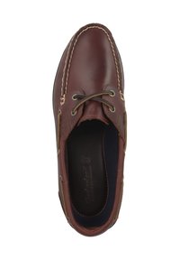 Brązowy skórzany but żeglarski z kontrastującymi, jasno-brązowymi akcentami, okrągłym noskiem, sznurowaniem i widocznym przeszyciem na cholewce. Wnętrze wyściełane granatową podszewką.