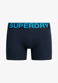 Boxer briefs in cotone blu navy con una ampia vita nera che presenta la scritta "SUPERDRY" in grassetto blu. Texture liscia e design aderente.