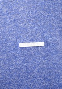 Modrý pletený svetr s jemnou texturou. Obsahuje bílou obdélníkovou nálepku s vyraženým textem "ragwear".