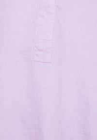 Jasnofioletowy len o gładkiej fakturze z widoczną kieszonką na lewej stronie. Minimalistyczny design, bez wzorów.
