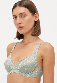 Groen bloemenkant beha met ingewikkelde borduursels, zachte stof, verstelbare bandjes en een subtiele glans. Kenmerkt een klein decoratief strikje in het midden.