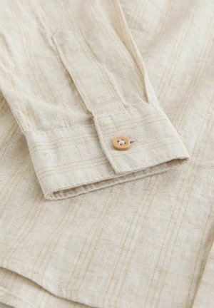 Helebeežikas särk linase tekstuuriga, õhukeste horisontaalsete triipudega ja nööbitava mansetiga, millel on naturaalsetest puidust nööp.