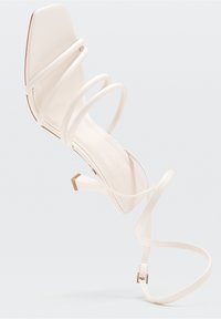 Sandal con tacco alto bianco, con punta quadrata, multiple cinghie sottili e un tacco sottile. Materiale in pelle liscia con dettagli di design minimalisti.