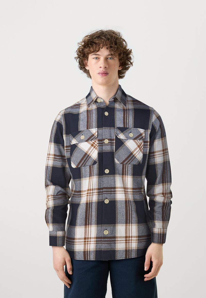 Camisa de cuadro en azul marino y gris, hecha de una tela de textura suave, que cuenta con cierres de botones y dos bolsillos en el pecho con solapas.