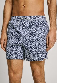 Pantaloni da bagno blu navy con un motivo geometrico bianco, vita elasticizzata e cordoncino, realizzati in tessuto leggero.