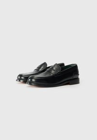 Zwarte leren loafers met een ronde neus, dubbele stiknaaddetails en een lage hak. Gladde textuur met een subtiele glans en groene binnenvoering.