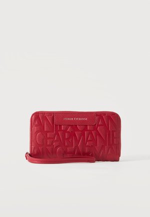 Rødt Armani Exchange armbånds-pung med præget store bogstaver og en aftagelig rem, sat mod en ensfarvet lys baggrund.