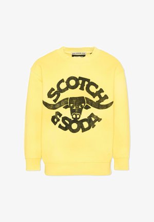 Żółta bluza z dużą czarną grafiką głowy byka i napisem "SCOTCH & SODA" z przodu.