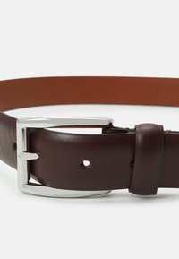 Cinturón de cuero marrón con una hebilla rectangular de plata brillante, que presenta varios agujeros para el ajuste y una textura suave.