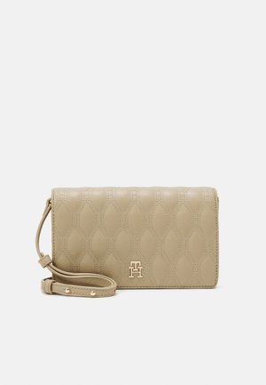 Beige quiltet læder crossbody taske med justerbar rem og lille guldfarvet metal logo foran, mod en ensartet lys grå baggrund.