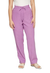 Pantalons en lin lilas avec une taille à lien, présentant une coupe décontractée et des poches latérales, associés à des sandales beiges à lanières.