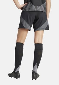 Zwarte sportshorts met grijze accenten, kniehoog zwarte sokken en zwarte voetbalschoenen. Textuur materiaal met een slim fit ontwerp.