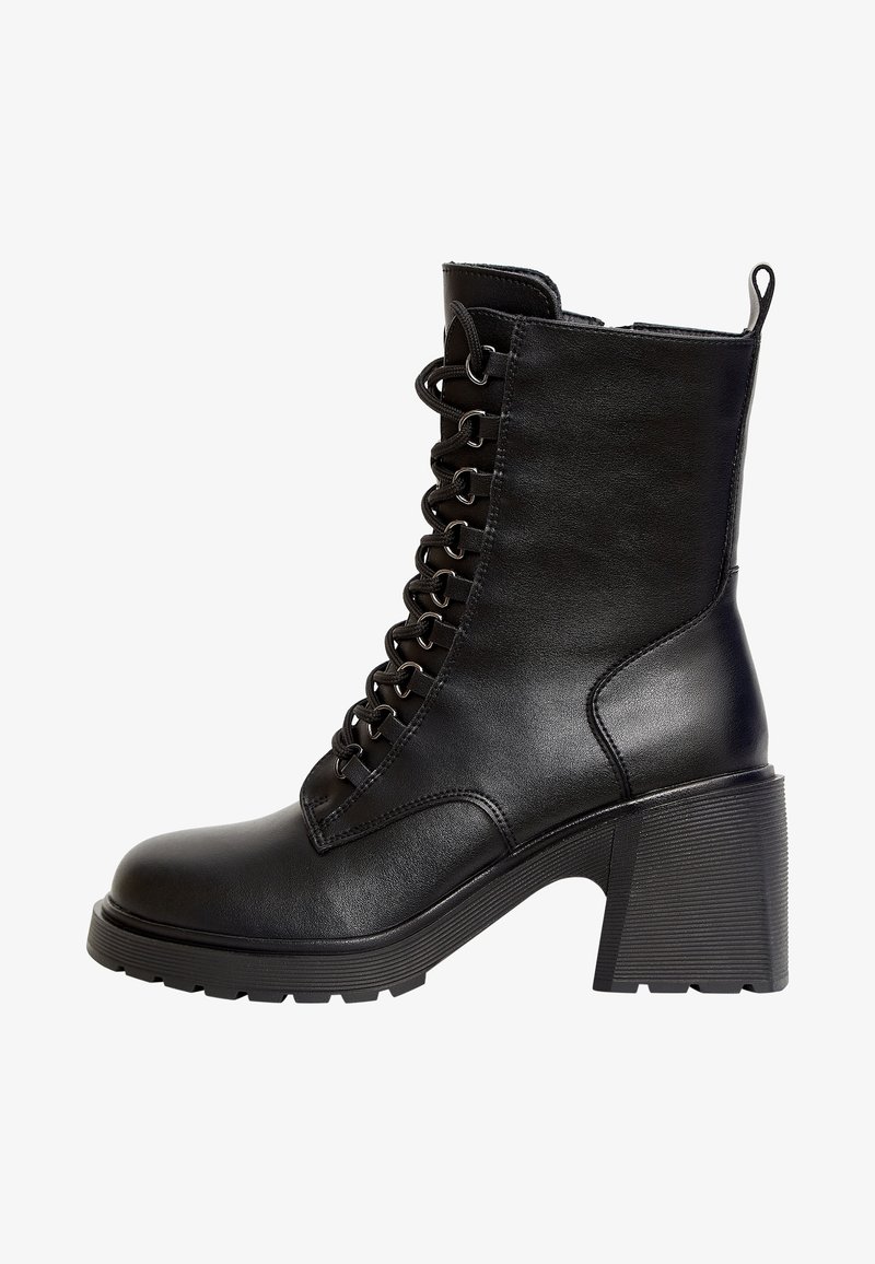 Bottine noire à talon, fabriquée en cuir synthétique, avec un laçage à l'avant, un bout rond et un talon carré texturé.
