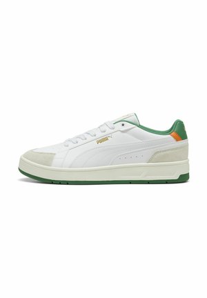 Zapatilla blanca con acentos en verde y naranja, texturas de cuero liso y gamuza, puntera redonda, diseño con cordones y una suela gruesa verde.