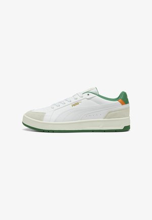 Zapatilla blanca con acentos en verde y naranja, texturas de cuero liso y gamuza, puntera redonda, diseño con cordones y una suela gruesa verde.