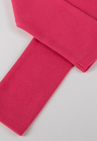 Felpa rosa aderente in tessuto, che presenta una texture morbida con una superficie liscia e cuciture pulite lungo i bordi.