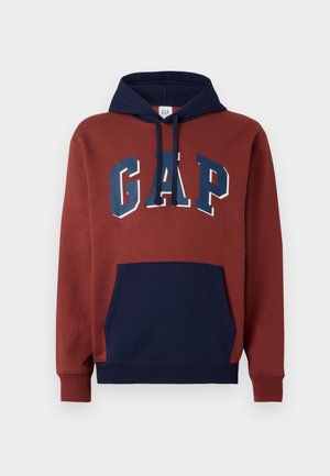 Czerwona i granatowa bluza z kapturem, z kieszenią z przodu, granatowymi sznurkami i dużym logo "GAP" w niebieskich literach na piersiach.