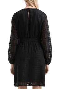 Vestido negro con mangas largas transparentes, patrones florales texturizados, un cinturón a la cintura y un cierre de ojo de cerradura en la parte posterior.