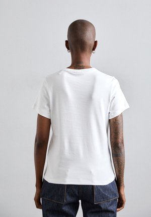 Valkoinen puuvillainen t-paita lyhyillä hihoilla, pyöreällä kaula-aukolla ja rentolla istuvuudella. Sisältää ommellun helman ja takasauman yksityiskohdan.