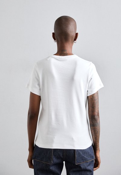 White cotton t-shirt with short sleeves, rounded neckline, and a relaxed fit. Features a stitched hem and a back seam detail.