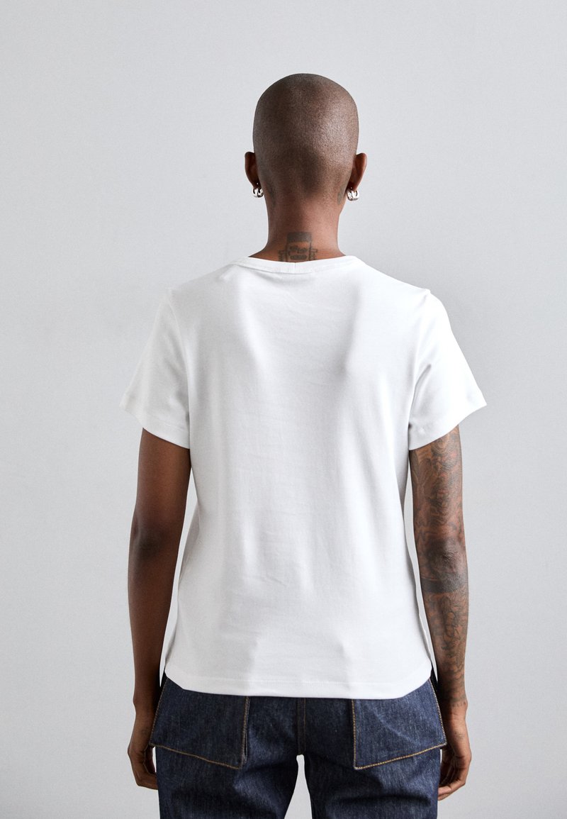 Valkoinen puuvillainen t-paita lyhyillä hihoilla, pyöreällä kaula-aukolla ja rentolla istuvuudella. Sisältää ommellun helman ja takasauman yksityiskohdan.