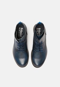 Botas de tobillo de cuero azul con una textura suave, punta redonda y diseño de cordones. Presentan una plantilla con patrón y acentos en azul en contraste.