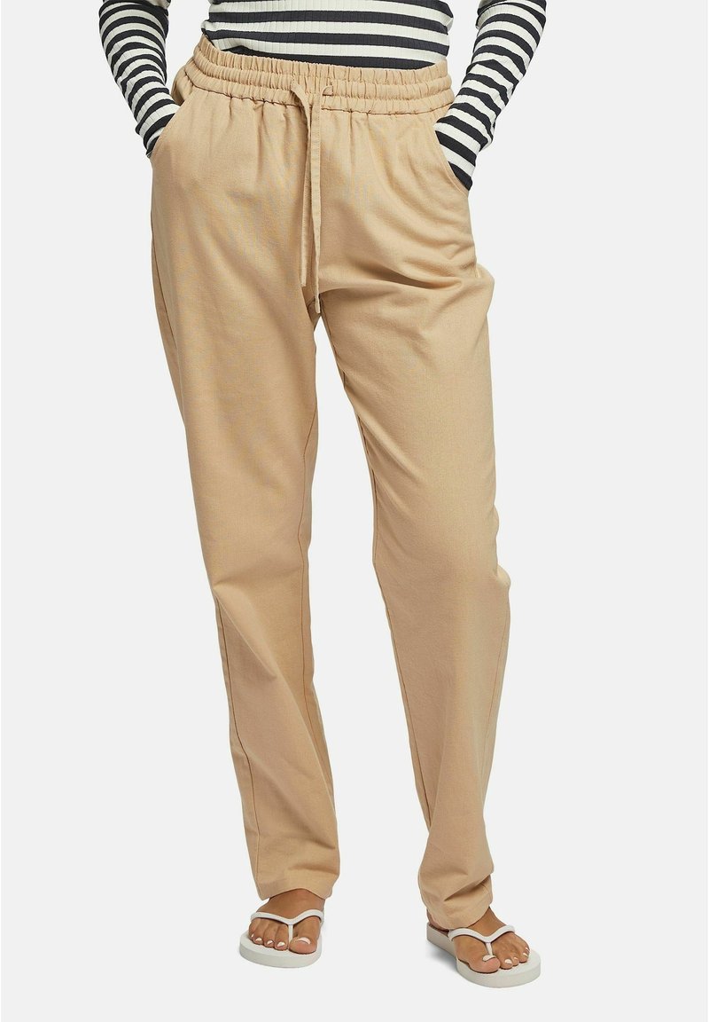 Beiga, lätta, dragsko-byxor med avslappnad passform. Har elastisk midja och sidofickor. Kombineras med vita sandaler.